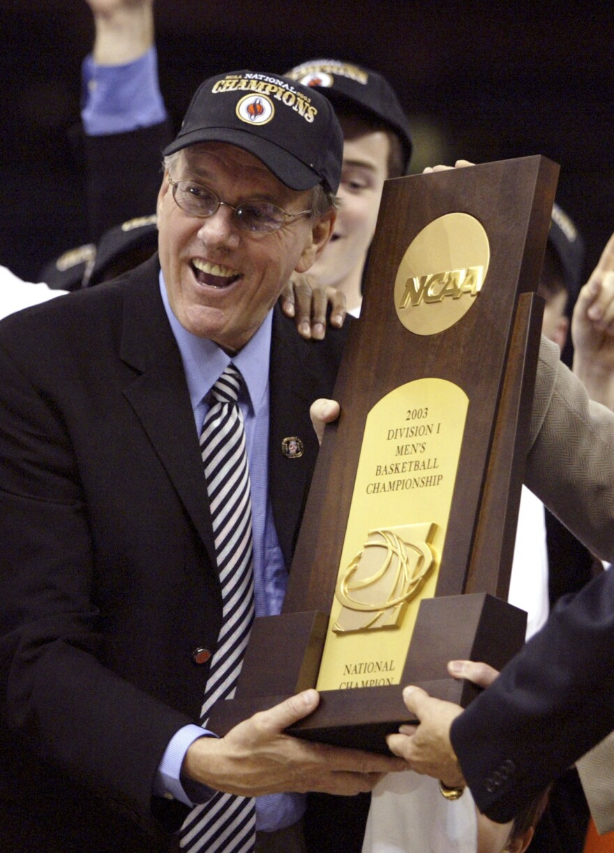 FILE -Syracuse head coach Jim Boeheim accepts the national championship trophy after the Orangemen beat Kansas 81-78 at the Final Four on Monday, April 7, 2003, in New Orleans. Syracuse coach Jim Boeheim is retiring after 47 years of leading the university's basketball program, the team announced Wednesday, March 8, 2023 after a loss knocked them out of the ACC Conference Tournament. (AP Photo/Michael Conroy, File)