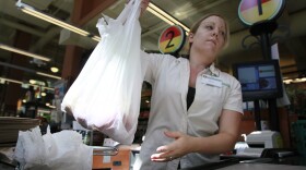 FILE -- This Aug. 3, 2009 photo shows clerk Allison Ure lifting groceries she's bagged in a plastic sack at the M Street Grocery in Seattle.