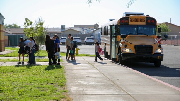 Students step off of a bus at Ed Pastor Elementary School.