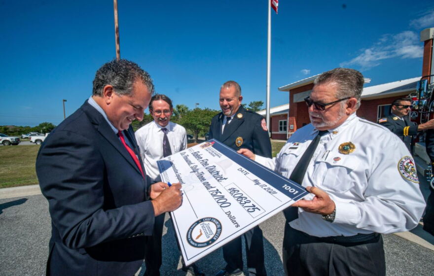 Florida CFO signs check to Panhandle Firefighters. Funding will be used for protective equipment.