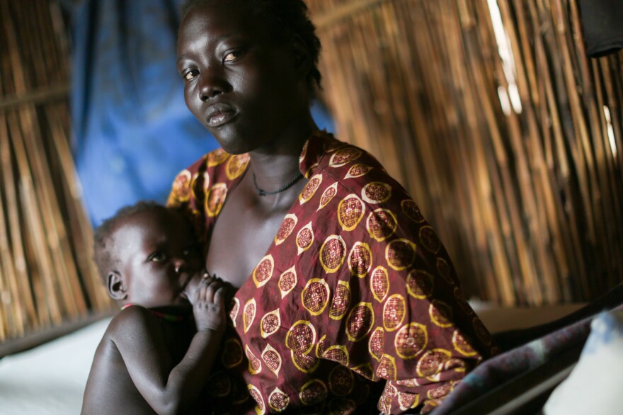 "I saw people killed in front of me," says 26-year-old Tavitha Nyaluak, explaining why she came to this camp. She's nursing her 2-year-old daughter in their shelter.