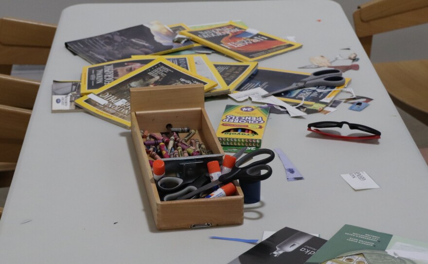 A table with glue, scissors, and magazines laying out.