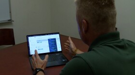A man sits in front of a laptop and demonstrates using a price finder tool