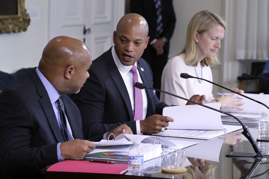 Maryland Gov. Wes Moore, center, talks to Treasurer Dereck Davis during a meeting of the Board of Public Works, which approved $2.9 million in compensation, Wednesday, July 5, 2023 in Annapolis, Md., for John Huffington, who was wrongly imprisoned for 32 years, including a decade spent on death row, for two murders he did not commit. Comptroller Brooke Lierman, who is a board member with Moore and Davis, is seated right. (AP Photo/Brian Witte)