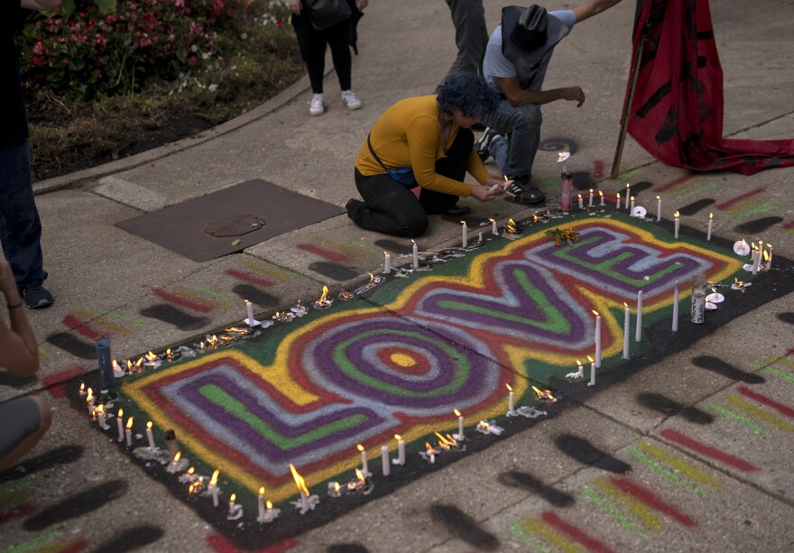People place candles around an artwork that says "LOVE" as a group gathers in Kenosha.