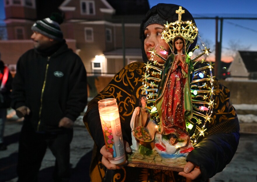 A woman carries her statue of Our Lady of Guadalupe along Friday's procession to St. Nicholas Church in Wilkes-Barre to be blessed. 