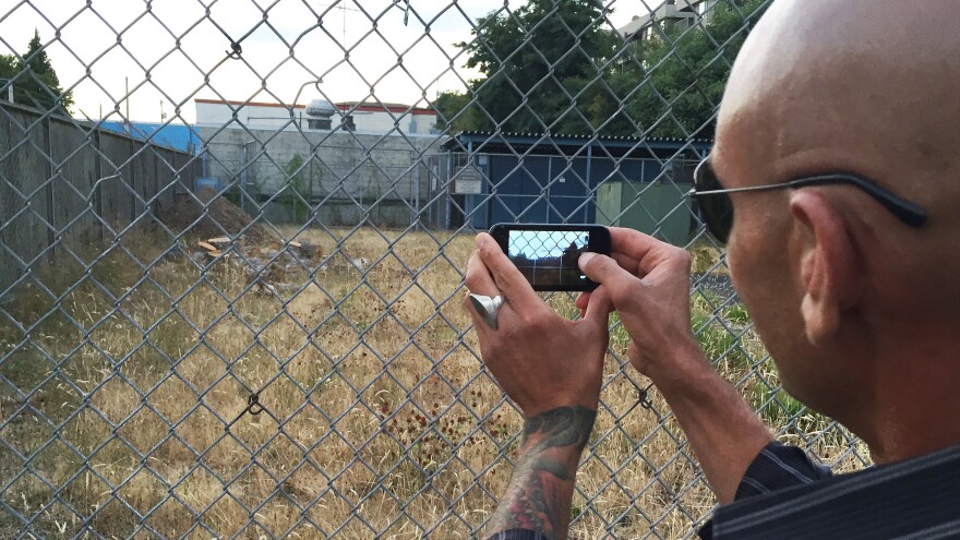 A Ballard man snaps a photo Monday night after a public meeting, as he mourns the loss of a tree, cut down recently by the city of Seattle. The tree was on a vacant lot that may one day host a tent city for the homeless.