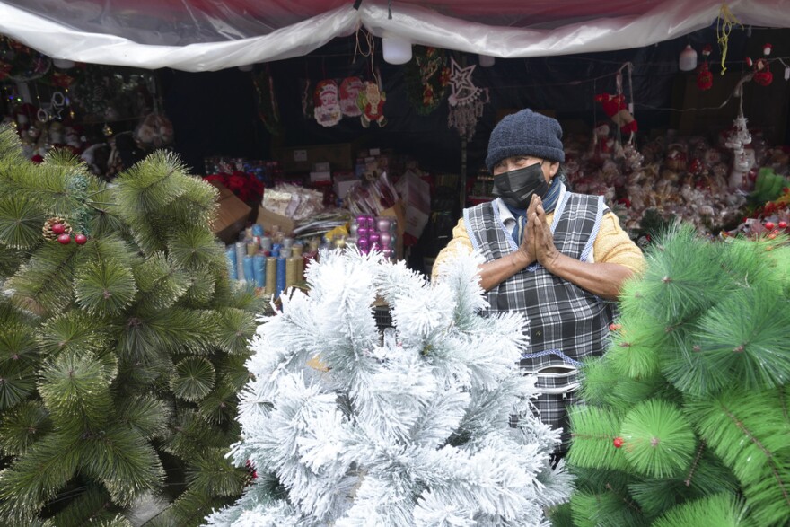 Christmas tree vendor Maria Constante waits for customers, in Quito, Ecuador, Tuesday, Dec. 3, 2024, amid power rationing that she says have slowed sales. The government of President Daniel Noboa decided to suspend daily power cuts during the end-of-year holidays