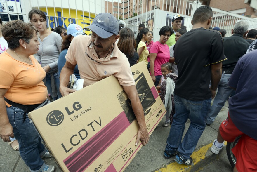 Shoppers loaded with purchases leave a Daka store in Caracas on Saturday.