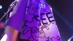 Christina Fallin on stage during the 2014 Norman Music Festival wearing a cape that read "SHEEP".