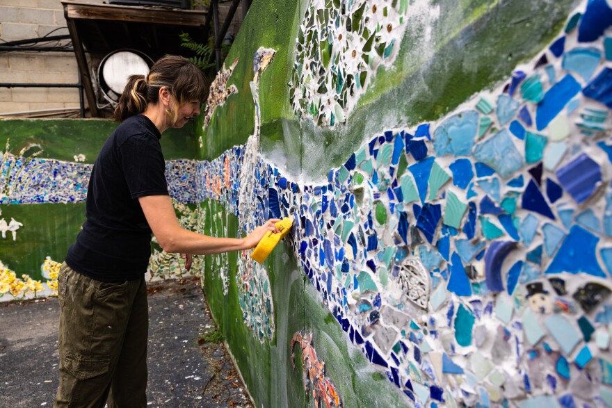 Whitesburg artist Lacy Hale works on a mural commemorating those who perished in the flood of 2022.