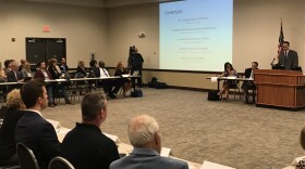 big room with seated people and display screens.