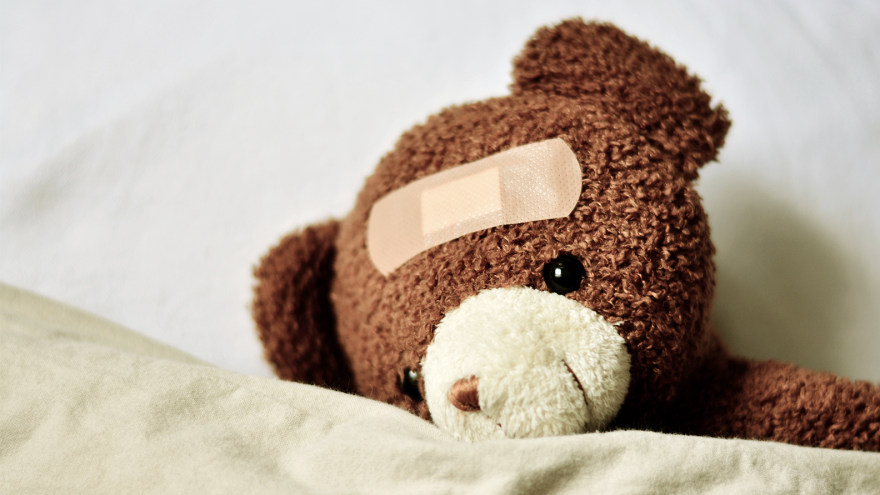 Stuffed teddy bear with a bandage on its head.