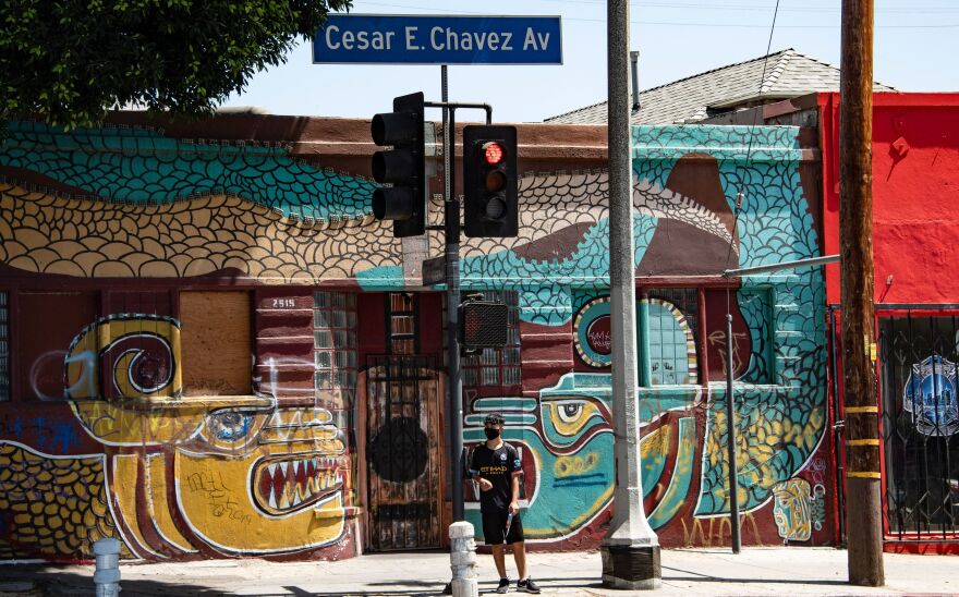 A man waits to cross the street in the largely Latino neighborhood of East Los Angeles on Aug. 7. California has implemented a new health equity metric to help address the outsize effect of coronavirus on the state's communities of color.