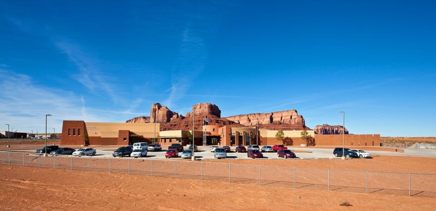 A brown school building with a red rock formation behind it. 