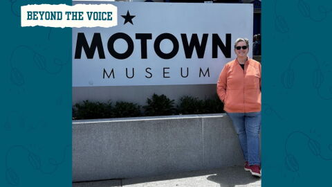 A woman wearing sunglasses smiles next to the Motown Museum sign.