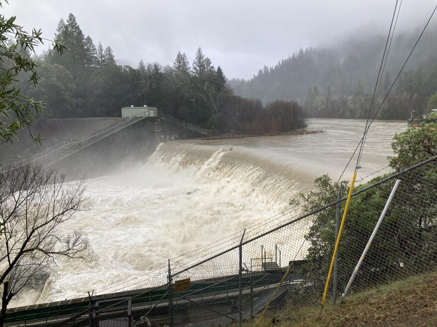 A dam on a cloudy dam with a large amount of water running over it