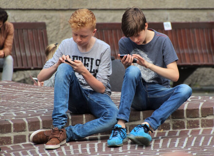 A picture of two children playing Pokemon GO on smartphones.