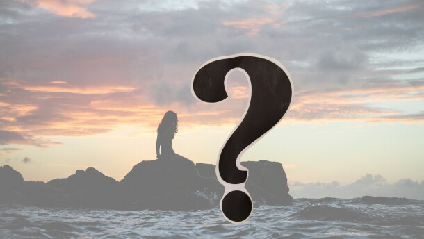 Silhouette of a woman on a line of rocks in the ocean at sunset; a question mark in the foreground 