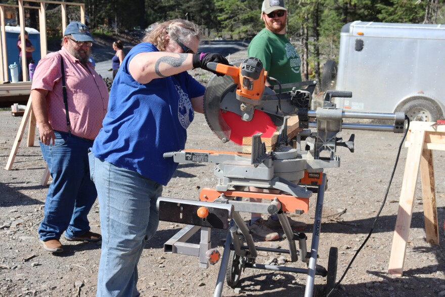 Future home owner Jane Belovaric learns how to use a power saw on day one of RurAL CAP's multi-home construction project in Seward.