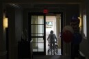 A woman uses a walker as she exits an assisted living building