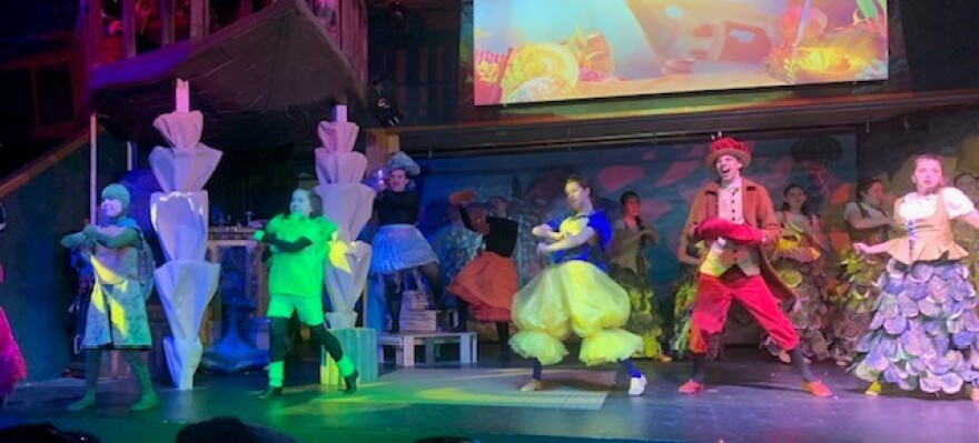 A cast of people dressed like sea creatures on a set that looks like under the sea.
