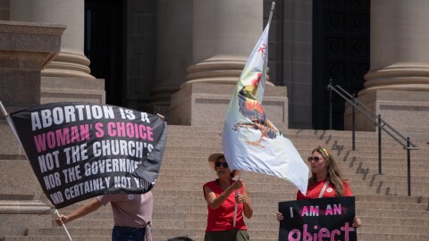 Demonstrators hold signs and wave flags during the 2024 OKC Women’s Strike at the Oklahoma Capitol.