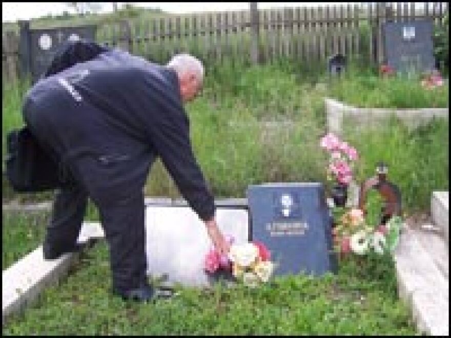 Milorad Radivojevic places flowers near the vandalized gravestone of a relative buried in the town of Svinjare. He has been unable to return to his village since an ethnic Albanian mob burned and looted Serb property there in 2004.