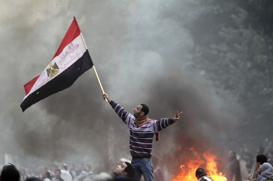 An Egyptian protester waves his national flag while making the victory sign outside the parliament building during clashes with soldiers near Cairo's Tahrir Square on Friday.