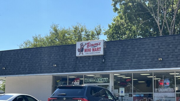 A store with car parked in front of it and a sign that reads "Beaver's Mini Mart" and a drawing of a beaver on it.