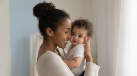 African American woman holding a baby and smiling.