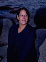 Amy Westervelt is standing on a coast and smiling.