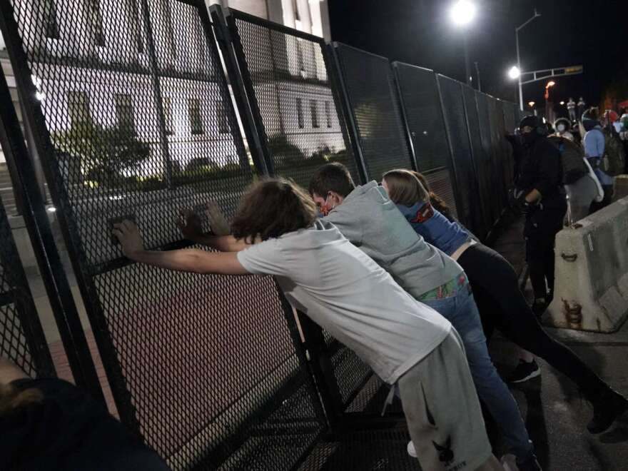 Protesters attempt to topple a fence outside the Kenosha County Courthouse late Tuesday, Aug. 25, 2020, in Kenosha, Wis. Protests continued following the police shooting of Jacob Blake two days earlier. (AP Photo/David Goldman)