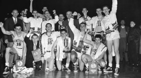 FILE - The Kentucky basketball team, which won the 1951 NCAA basketball championship, celebrates in Minneapolis, March 28, 1951, as it displays the team trophy and individual plaques. At center right is coach Adolph Rupp. Team members are, front row from left: Louis Tsioropoulos, C.M. Newton, Bobby Watson, Cliff Hagen, Lucian Whitaker and Frank Ramsey. Rear, from left: Dwight Price, Bill Spivey, Guy Strong, Roger Layne and Shelby Linville. (AP Photo/Chet Magnuson, File)