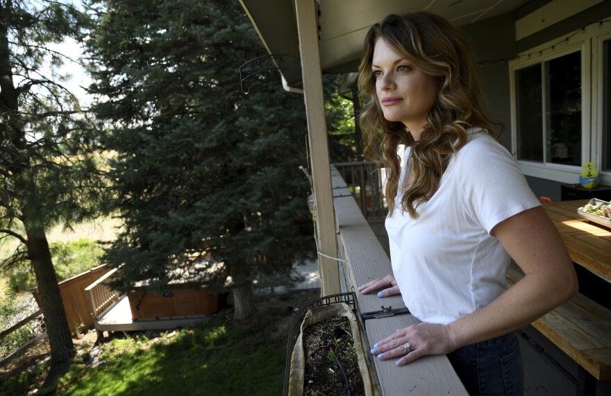 A woman looks out over a meadow from her patio.