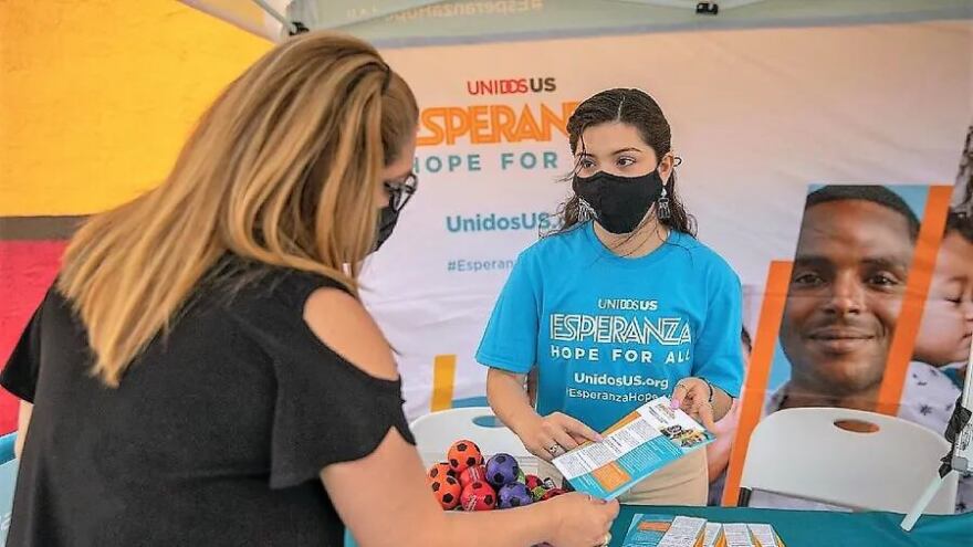 An UnidosUS representative hands out COVID vaccine information to a Latina resident in Phoenix, Ariz., in 2022 at one of the organization's nationwide mobile tour stops.