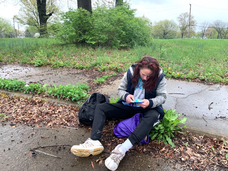 A person seated on the edge of a sidewalk