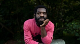 Hanif Abdurraqib sitting a boulder, propping up his chin with his hand