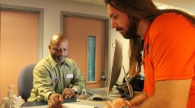 Tracy Davis, a University of Florida financial aid adviser, shows criminology student Christian Knappins a Bright Futures flier in the University of Florida's Criser Hall in January. A Florida Senate panel backed a bill Wednesday that would expand Bright Futures scholarships, impose stricter graduation standards and increase financial aid for first-generation students.(File/WUFT News)