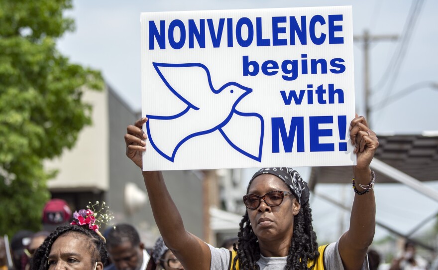 A woman holds up a "NONVIOLENCE begins with ME!" sign.