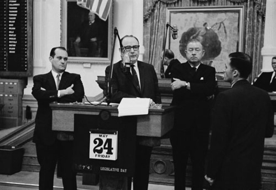  Legislative representatives stand behind a podium. 