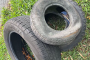 Three black tires filled with water are lying out on the grass.