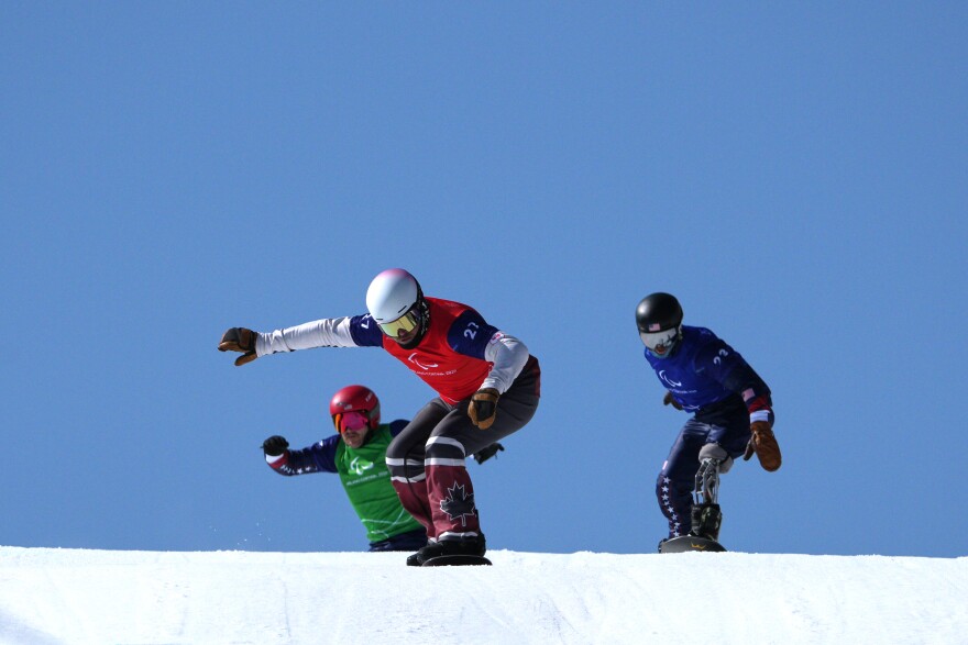 Tyler Turner, of Canada, leads Noah Elliott, of the United States, right, and Mike Schultz, of the United States, in a men's snowboard cross SB-LL1 semifinal at the 2026 Winter Paralympics, in Cortina d'Ampezzo, Italy, Sunday, March 8, 2026.