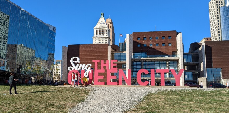 People pose before a 3-D sign reading "Sing the Queen City."