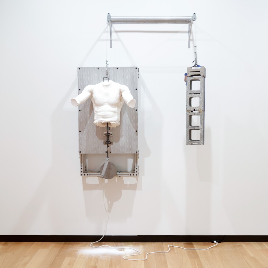 A plaster statue of a man's torso hangs.