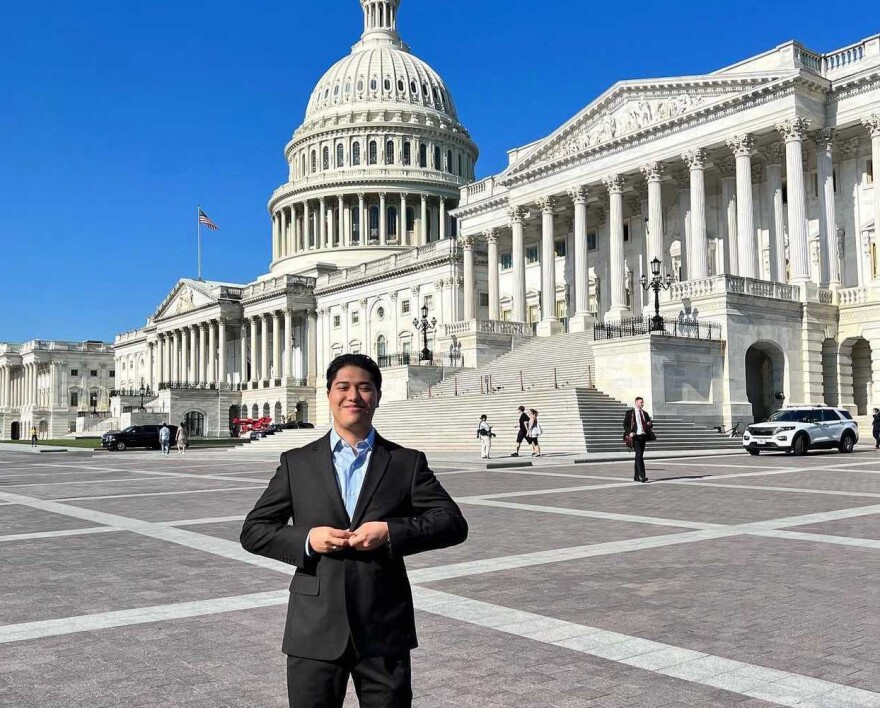 Omar Salazar, wearing a light blue shirt and a dark suit, poses in front of the U.S. Capitol.