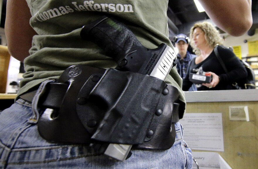 A gun store employee in Spring, Texas, carries a gun on her hip while working the counter in 2016.