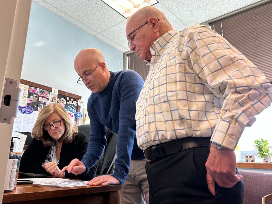 Rochester Teachers Association officers Aimee Rinere (left) and Jason Valenti (center) on speakerphone with a union member checking for possible errors on her W-2 form as RTA President Adam Urbanski (right) stops by on Monday, Feb. 2.