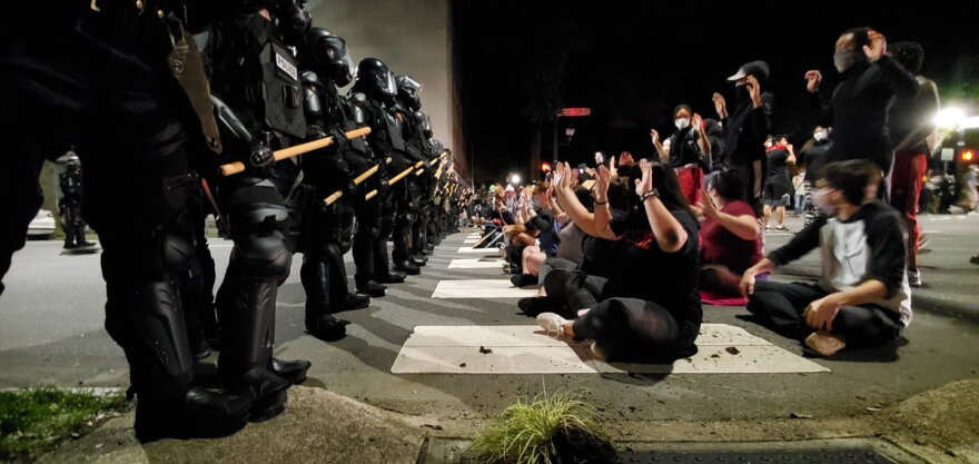 Protesters seated in front of officers at Hillsborough and Salisbury in downtown Raleigh on Sunday night.