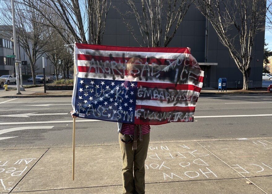 A young protestor holds an upside-down American flag at the Eugene federal building on Monday, Feb. 2, 2026.
